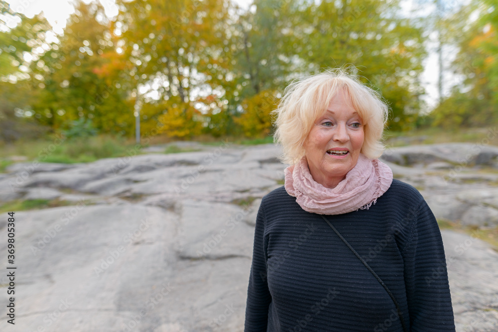 Senior happy woman smiling on top of boulder in the mountains Senior happy woman smiling on top of boulder in the mountains