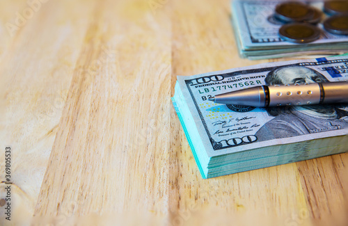 One hundred dollar bills and pen on the old wooden.Business concept - money, pen and cash .The money and pen on grungy wood board. Background and Texture with space for text or image. photo