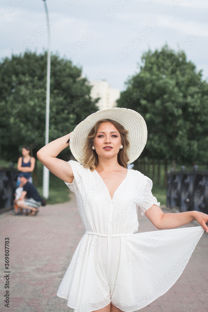 beautiful young girl in a long summer white dress and a big white hat