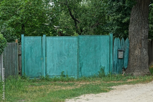 iron green gate and rural wooden fence on the street