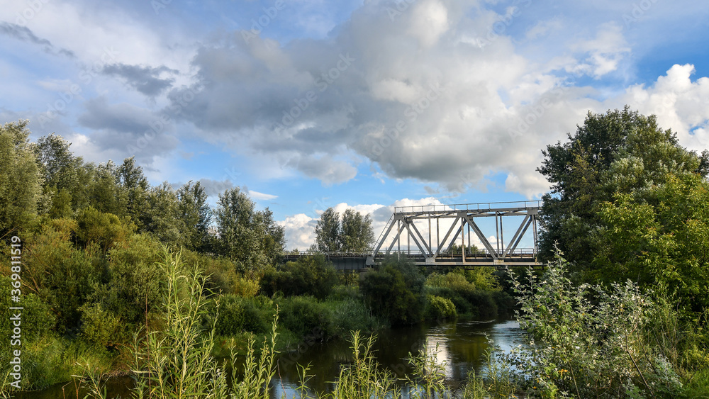 Summer sunset scenery with railway bridge over the river. Wide angle view.  Background of blue sky.