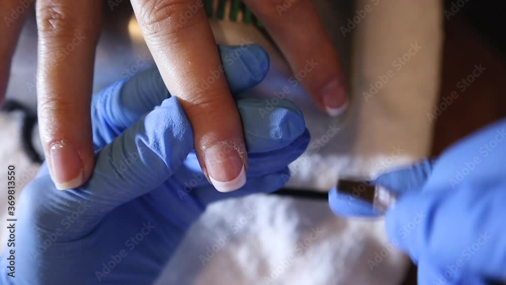 Beautician applying white color gel with a brush on girl nail in a beauty salon. Preparation and procedure for a new french manicure. Beauty and manicure concept. Close up, selective focus Beautician applying white color gel with a brush on girl nail in a beauty salon. Preparation and procedure for a new french manicure. Beauty and manicure concept. Close up, selective focus