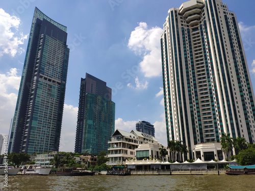 Some tall buildings on the shore of the river in Bangkok under sunny day