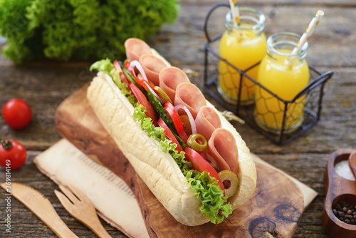 Homemade turkey ham sandwich with tomato, cucumber, red onion, olives, lettuce, cheese and white sauce.
