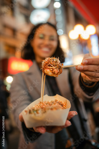 Mujer ofreciendo un delicioso takoyaki, tentempié tradicional de pulpo japonés