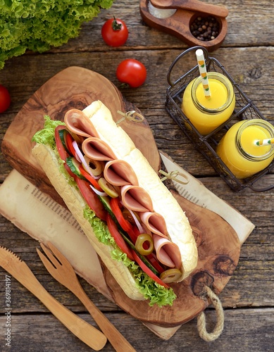 Homemade turkey ham sandwich with tomato, cucumber, red onion, olives, lettuce, cheese and white sauce.
