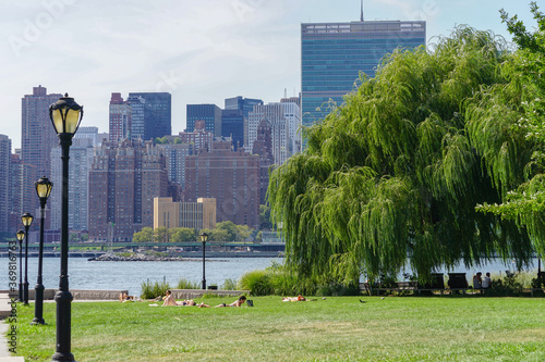 Long Island City, New York: Sunbathers on the lawn of Gantry Plaza State Park, with a view of United Nations Headquarters and the Manhattan skyline. photo