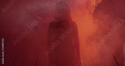 Silhouette of a female demon with long horns moving in red smoke, 4k photo