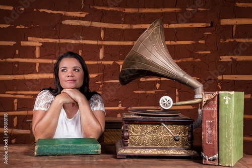 A girl listening to music on an old gramophone with some album discs on the table photo