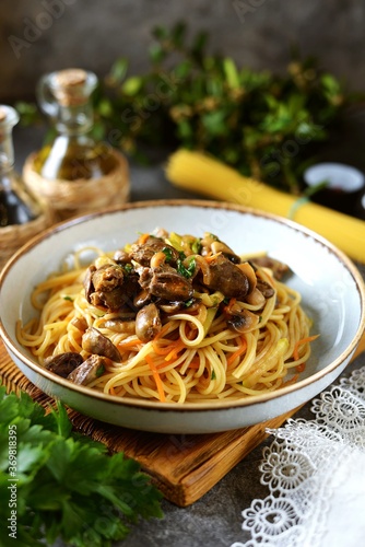 Spaghetti with stewed chicken hearts with onions, carrots, zucchini and garlic. Healthly food.