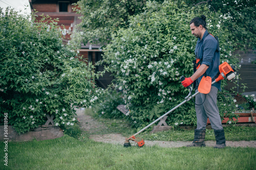 A man mows the grass with a hand mower in the garden