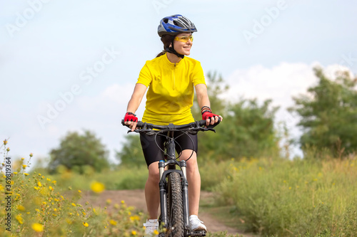 beautiful and happy girl cyclist rides a bicycle on the road in nature. Healthy lifestyle and sports. Leisure and hobbies