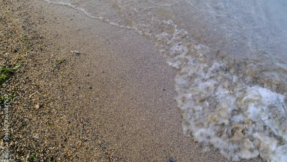 Wave runs on the sandy shore of the sea, Close Up/Pan Right Wave runs on the sandy shore of the sea, Close Up/Pan Right