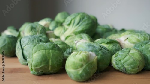 Slow Motion Push-In Shot Towards Heap of Fresh Raw Brussels Sprouts on Wooden Tabletop photo