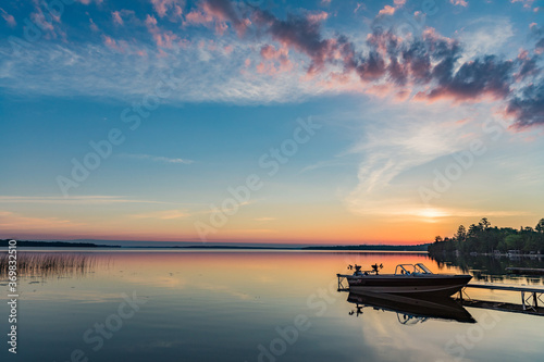 Cottage vacation holiday with a beautiful early sunrise overlooking the fishing boat and dock in Canada  Balsam Lake in Kawartha Lakes 