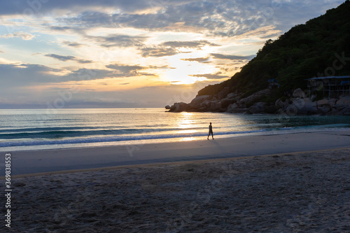 Young woman is walking alone on the beach during sunrise. Phangan island, Thailand. photo