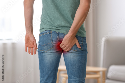 Man suffering from hemorrhoid at home, closeup