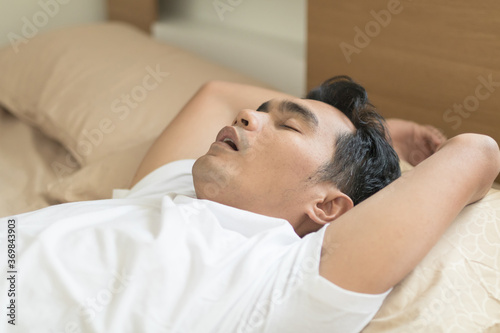 Asian young man sleeping and snoring on the bed 