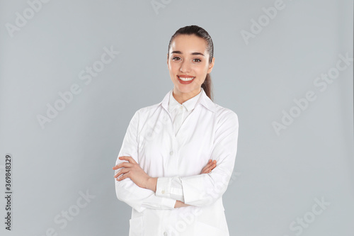 Canvastavla Happy young woman in lab coat on light grey background