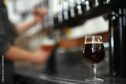 Glass of cold tasty dark beer on bar counter, space for text