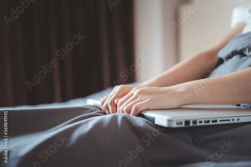 Upset Asian woman working on the bed by using laptop computer. A stress in freelance career during unstable economic. Unhappy and stressful Asian woman working in the bedroom. © DG PhotoStock