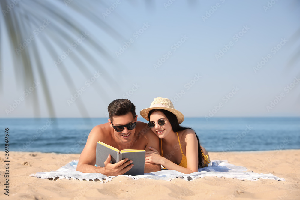 Happy couple reading book together on sunny beach Happy couple reading book together on sunny beach