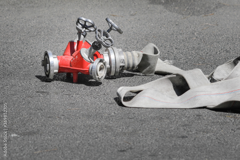 Firefighters hose and hydrant hose adaptor on concrete during a fire.