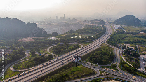 Aerial view of cars drive along a highway among limestone mountains in Ipoh city, Malaysia.
