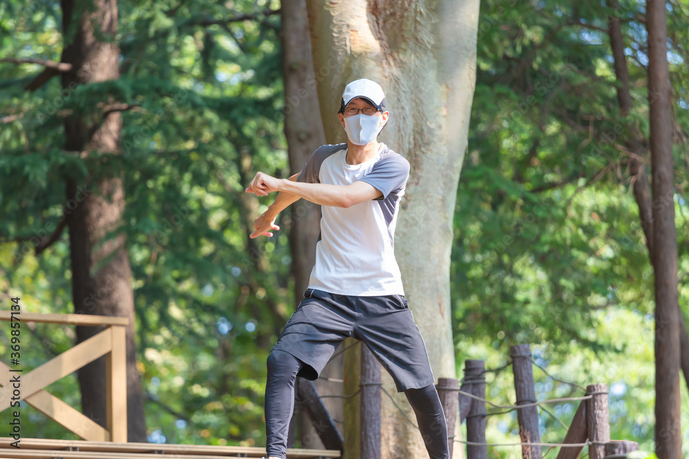 熱中症の恐れのある中年男性が、マスクをつけながら野外で運動をしている 熱中症の恐れのある中年男性が、マスクをつけながら野外で運動をしている