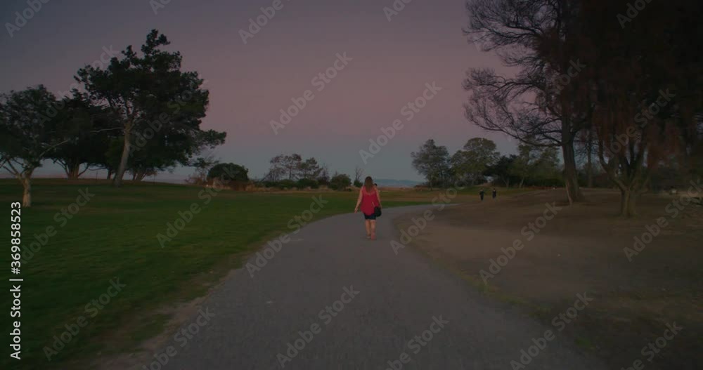 Steady shot closing in of woman walking from behind. In slow motion