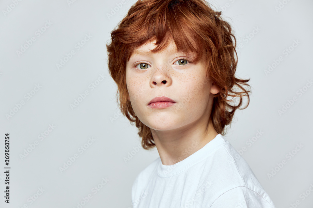 Cute redhead child cropped view white t-shirt face closeup gray background Cute redhead child cropped view white t-shirt face closeup gray background