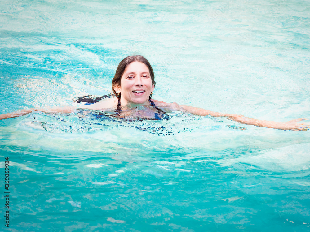 Cheerful senior woman relaxing in swimming-pool