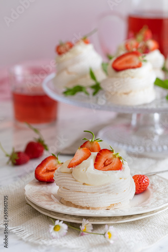 Mini pavlova meringue nests with whipped cream and fresh strawberries.