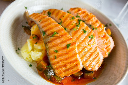 Tasty steak of grilled salmon in sauce with pepper and lemon, served on plate with potatoes