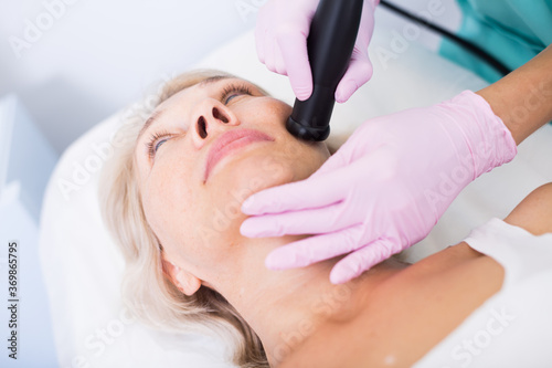 Close up of mature female getting facial cryolipolyse treatment in cosmetic cabinet