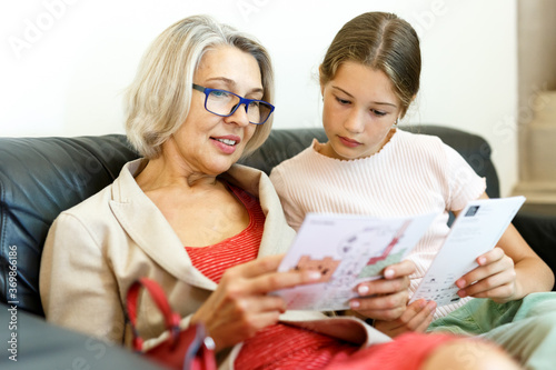 Mature woman and teenage girl sitting with paper guide during museum visit photo