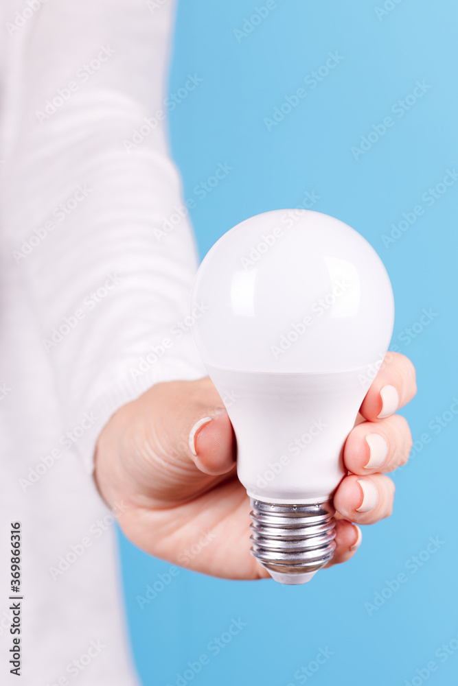 Hand with white LED light bulb. Isolated on blue background. Hand with white LED light bulb. Isolated on blue background.