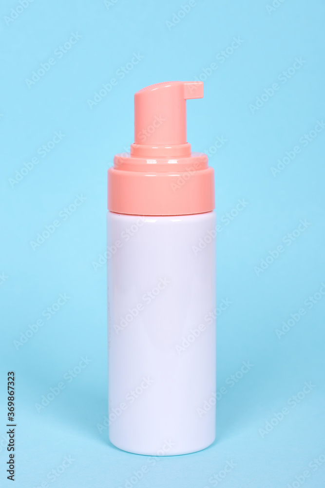 Face foam dispenser bottle, cosmetic lotion. Isolated on blue background. Face foam dispenser bottle, cosmetic lotion. Isolated on blue background.