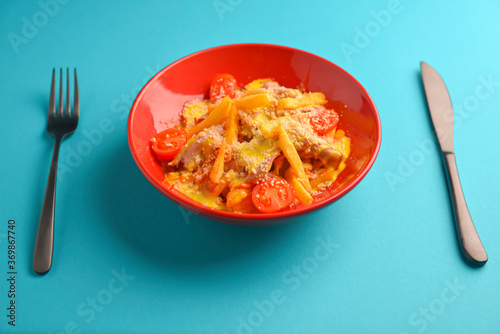 Melting cheddar cheese over the top of french fries covered in spicy sauce with meat and tomatoes. Blue background.