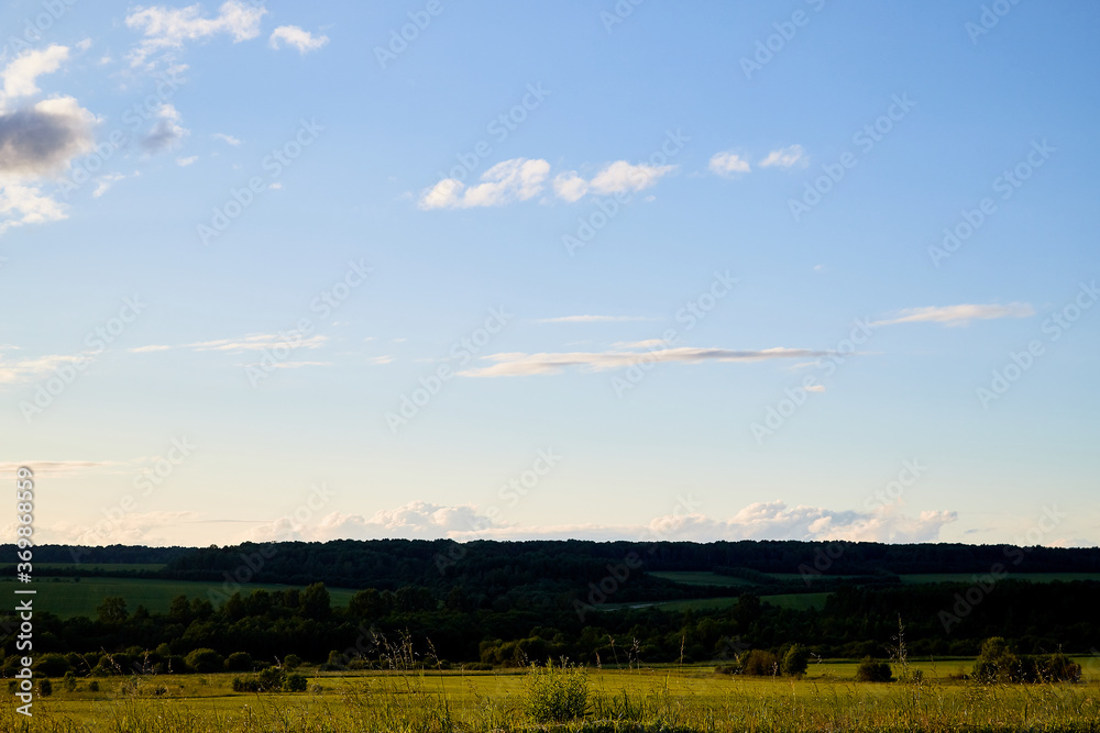 Beautiful landscape with blue sky, white clouds, sunset and field.