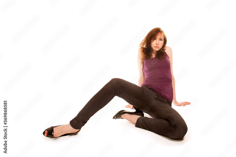Beautiful young woman wearing a black jeans and high heels, sitting in cool pose on the floor, portrait in front of white background Beautiful young woman wearing a black jeans and high heels, sitting in cool pose on the floor, portrait in front of white background