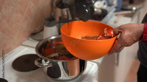 The cook takes out the cooked red blue crabs from the pan and folds them into an orange bowl. photo