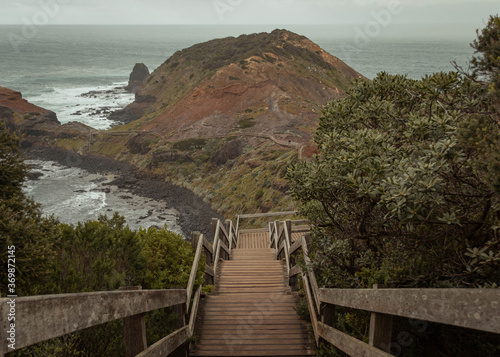 Wooden boardwalk leading to an island with a beach in windy and rainy conditions