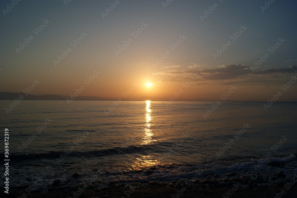 Beautiful dawn over the sea. Sunny path on the water. Light wave and swell on the surface of the water