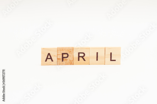 Word APRIL made of wooden blocks on white background. Month of year