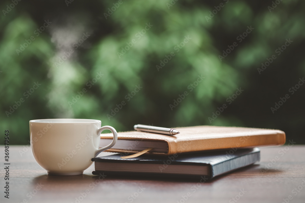 Hot coffee, smoke, with books and pens for note taking with beautiful nature background. Hot coffee, smoke, with books and pens for note taking with beautiful nature background.