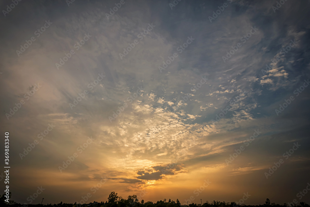 Sunset sky in evening.Clouds covering the sun in the lower middle of frame and golden light on clouds.
