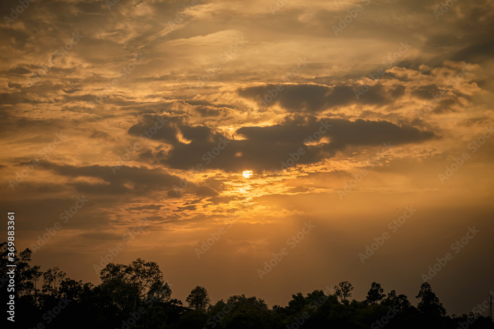 Sunset sky in evening.Clouds covering the sun in the middle of frame and golden light on clouds.