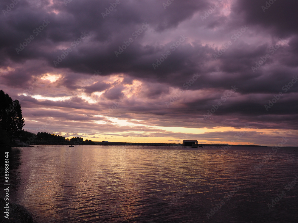 Sunset, summer, beautiful clouds at sunset. Thunderous sunset. Pier on the big Kama river. Ural, Russia, Perm Territory, Elovo.