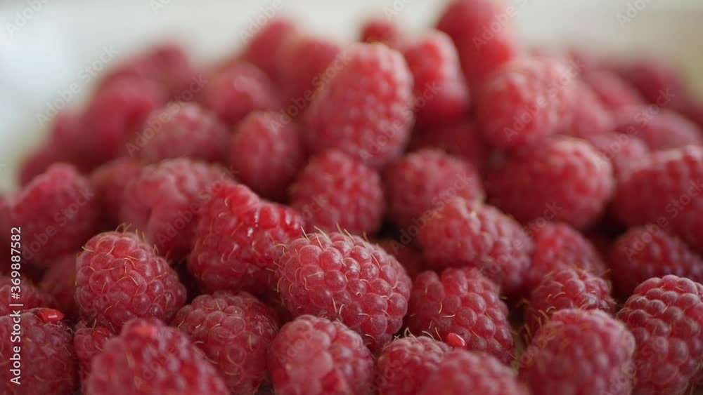 Male hand takes raspberry from bowl with a lot of fresh raspberries. Closeup Male hand takes raspberry from bowl with a lot of fresh raspberries. Closeup
